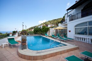 Una piscina al aire libre de temporada, sillones reclinables de piscina