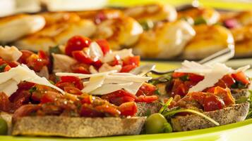 Een close-up van een bord met diverse hapjes, waaronder bruschetta belegd met tomaten, kaas en olijven.