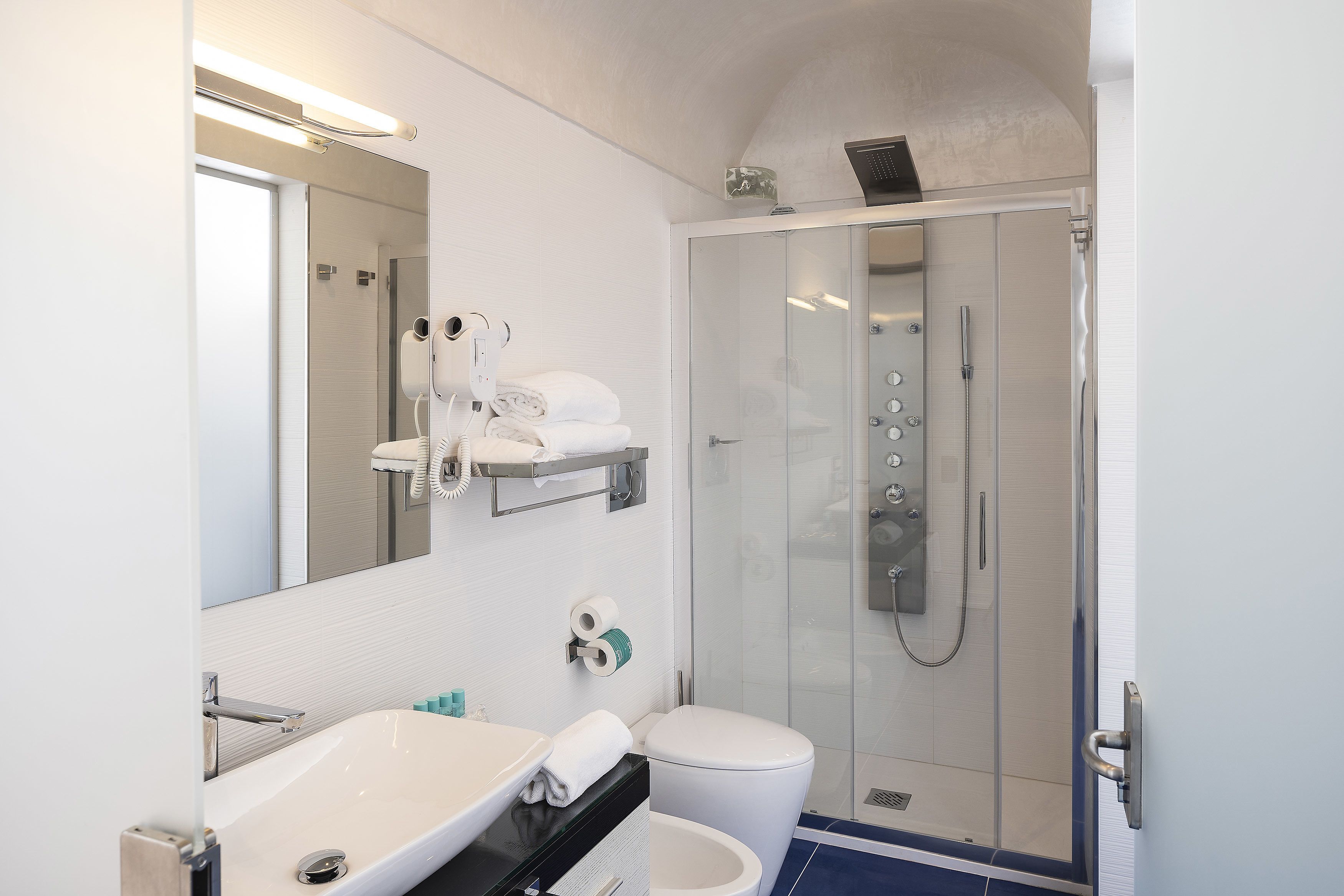 A modern bathroom with a white sink, a toilet, and a glass-enclosed shower.