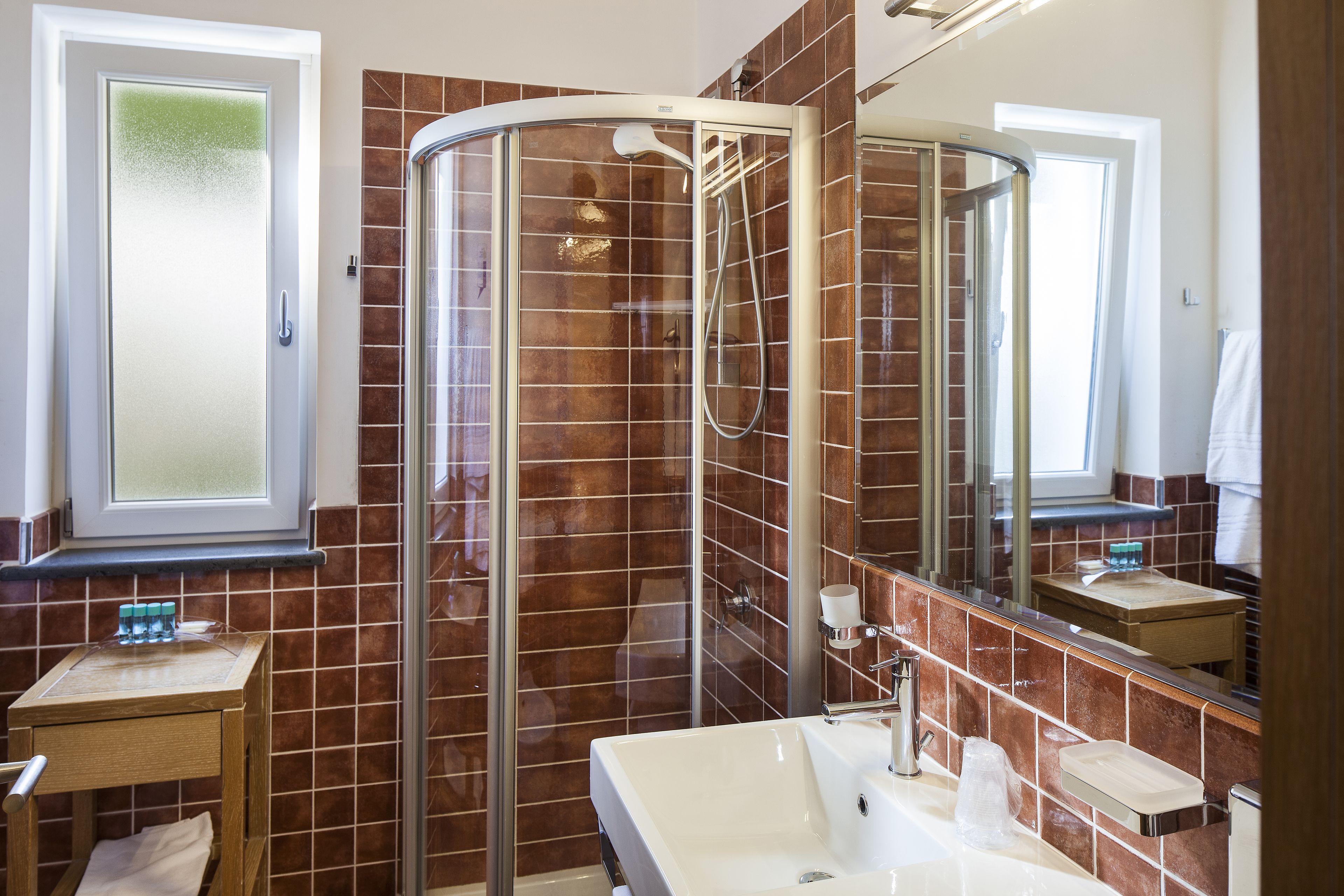 A modern bathroom with a glass-enclosed shower, a large mirror, and a vanity with a sink.