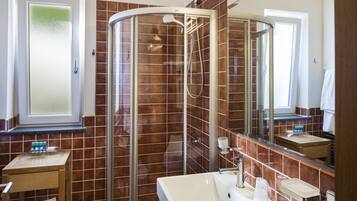 A modern bathroom with a glass-enclosed shower, a large mirror, and a vanity with a sink.