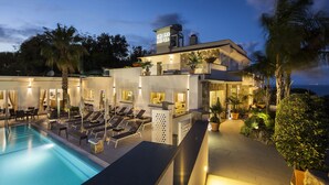 Un hotel con piscina, tumbonas y un espacio exterior bien iluminado.