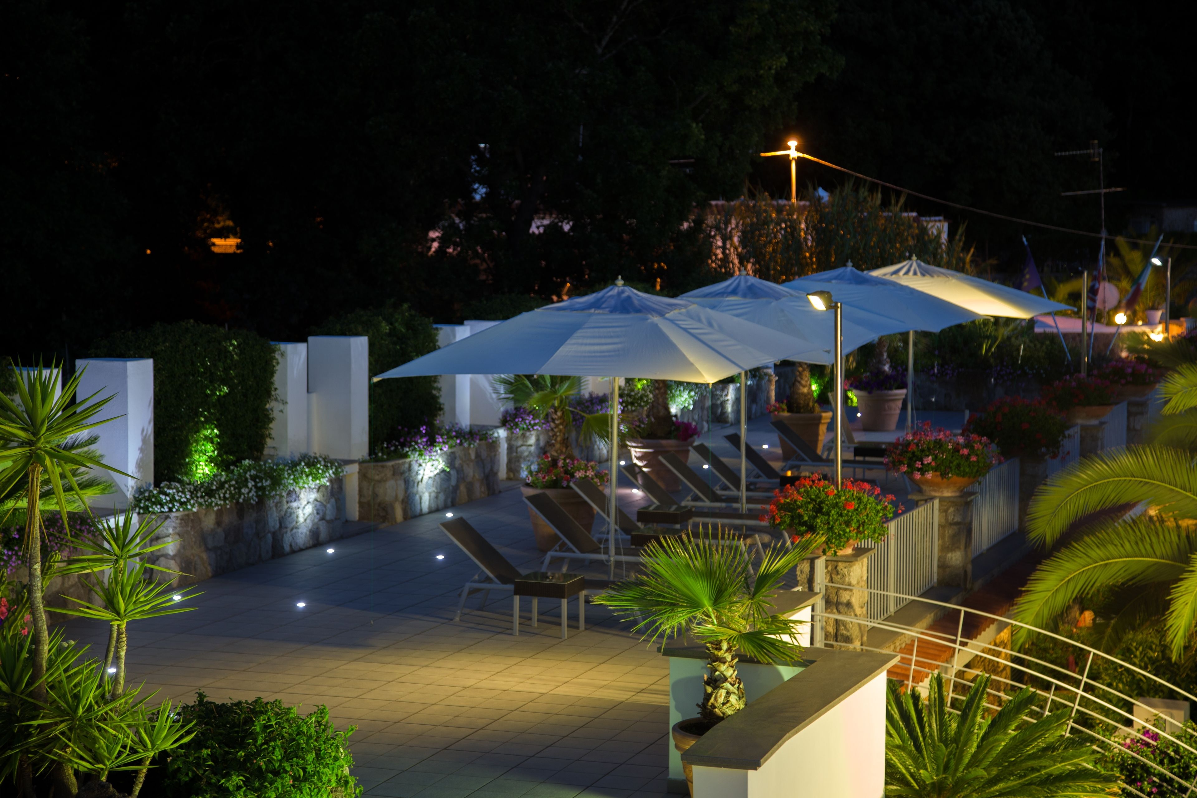 Un espacio al aire libre con patio, sombrillas, asientos y plantas en macetas.