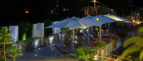 Un espacio al aire libre con patio, sombrillas, asientos y plantas en macetas.