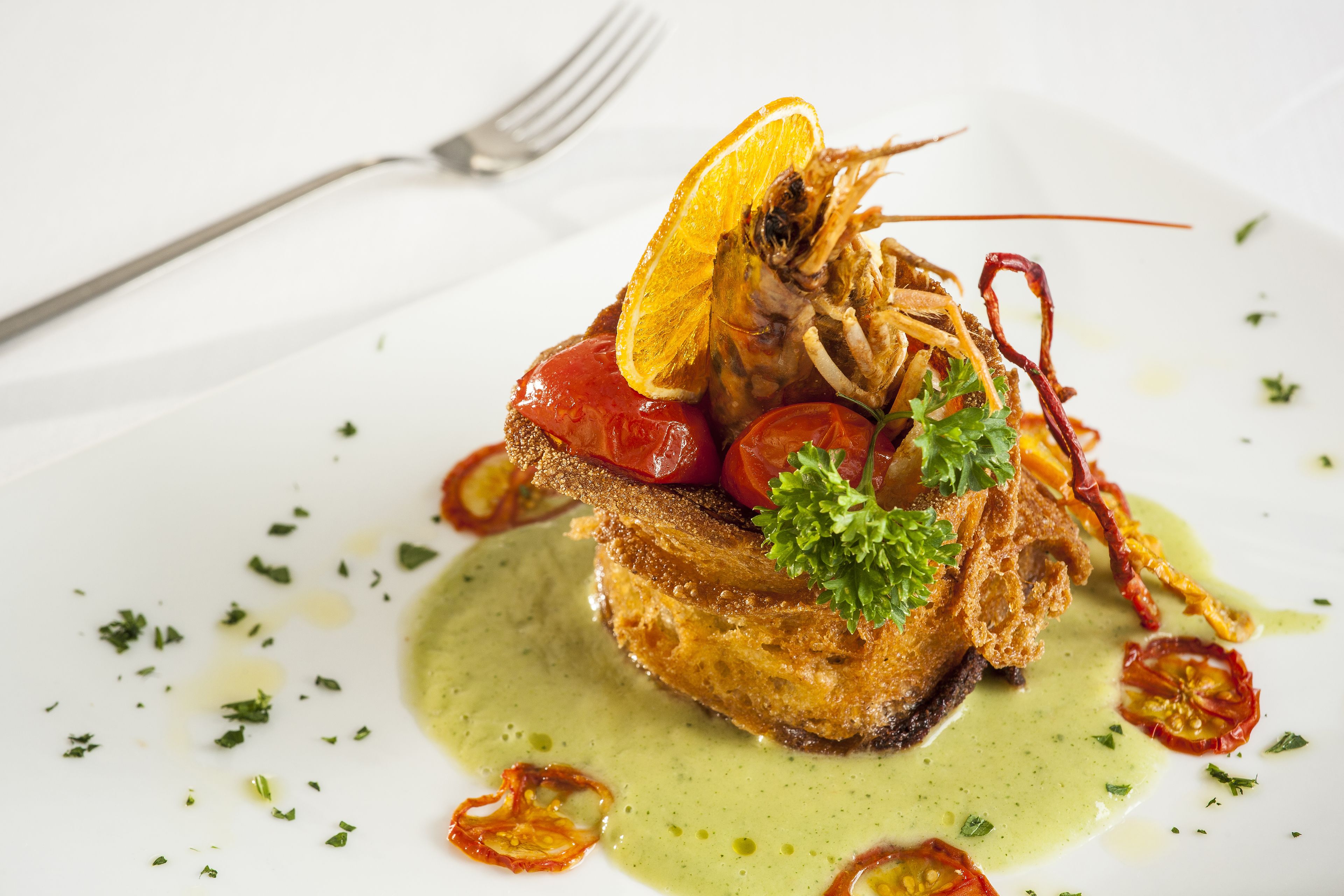 Un plato con pescado, tomates y una guarnición.