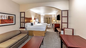 A hotel room with a large bed, a sofa, a desk, and a TV. - Red Lion Inn & Suites Mineral Wells (Mineral Wells)