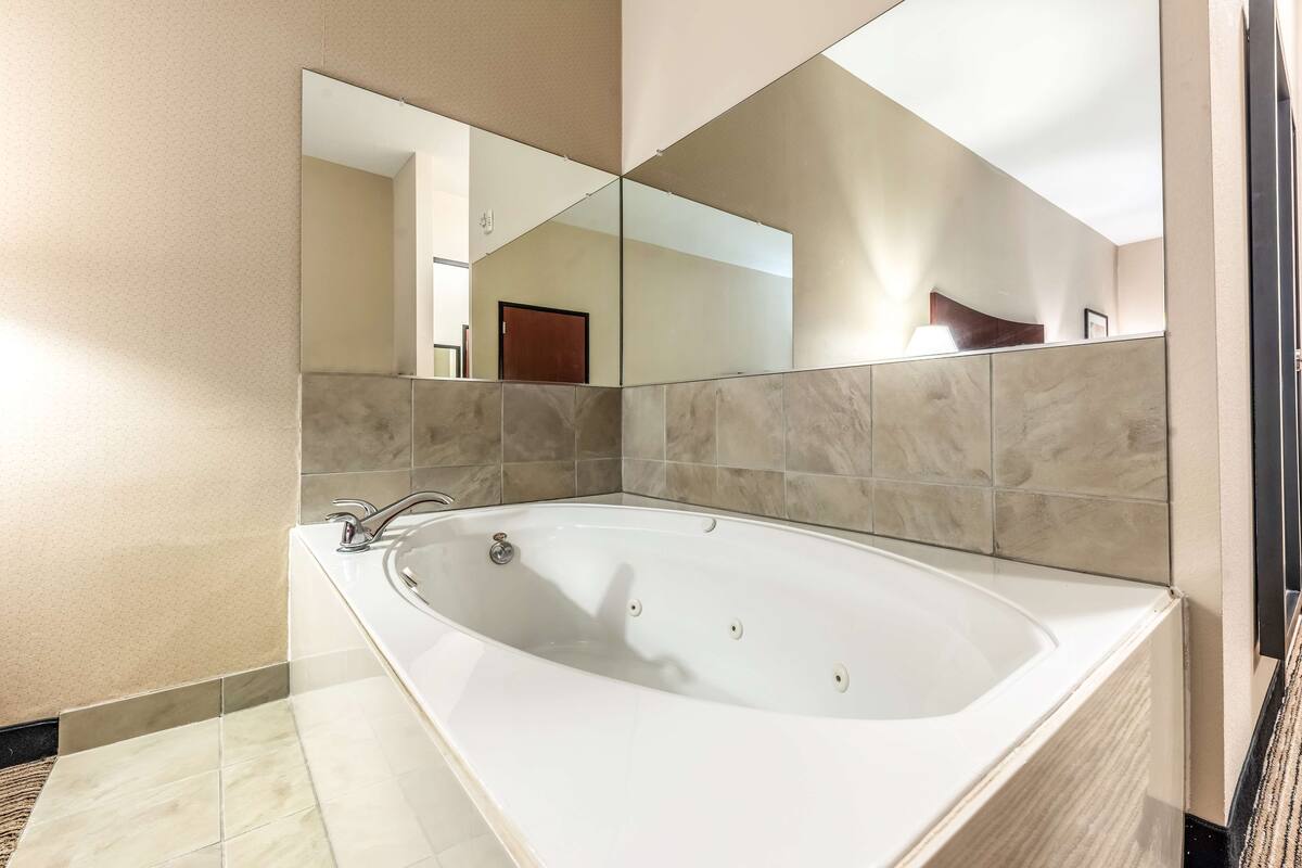 A modern bathroom with a large bathtub, a wall-mounted mirror, and tiled walls.