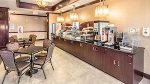 A hotel breakfast area with a buffet counter, seating, and a coffee station. - Red Lion Inn & Suites Mineral Wells (Mineral Wells)