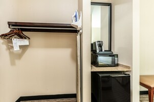 Una kitchenette compacta con microondas, cafetera y un refrigerador pequeño.