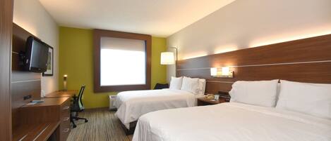 A hotel room with two beds, a desk with a chair, a television, and a window with a view.