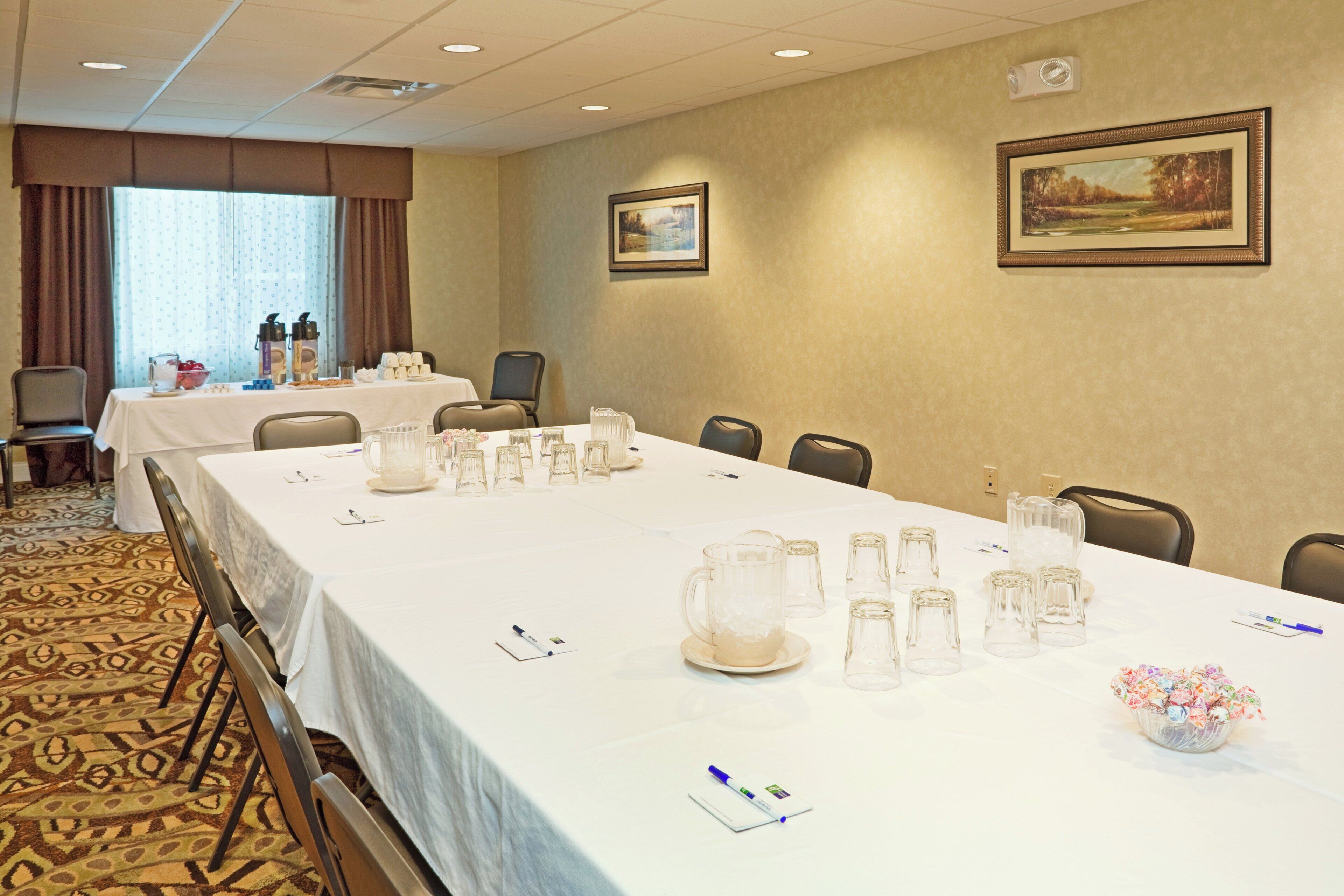 Une salle de conférence avec une longue table préparée pour une réunion, équipée de verres et de stylos.