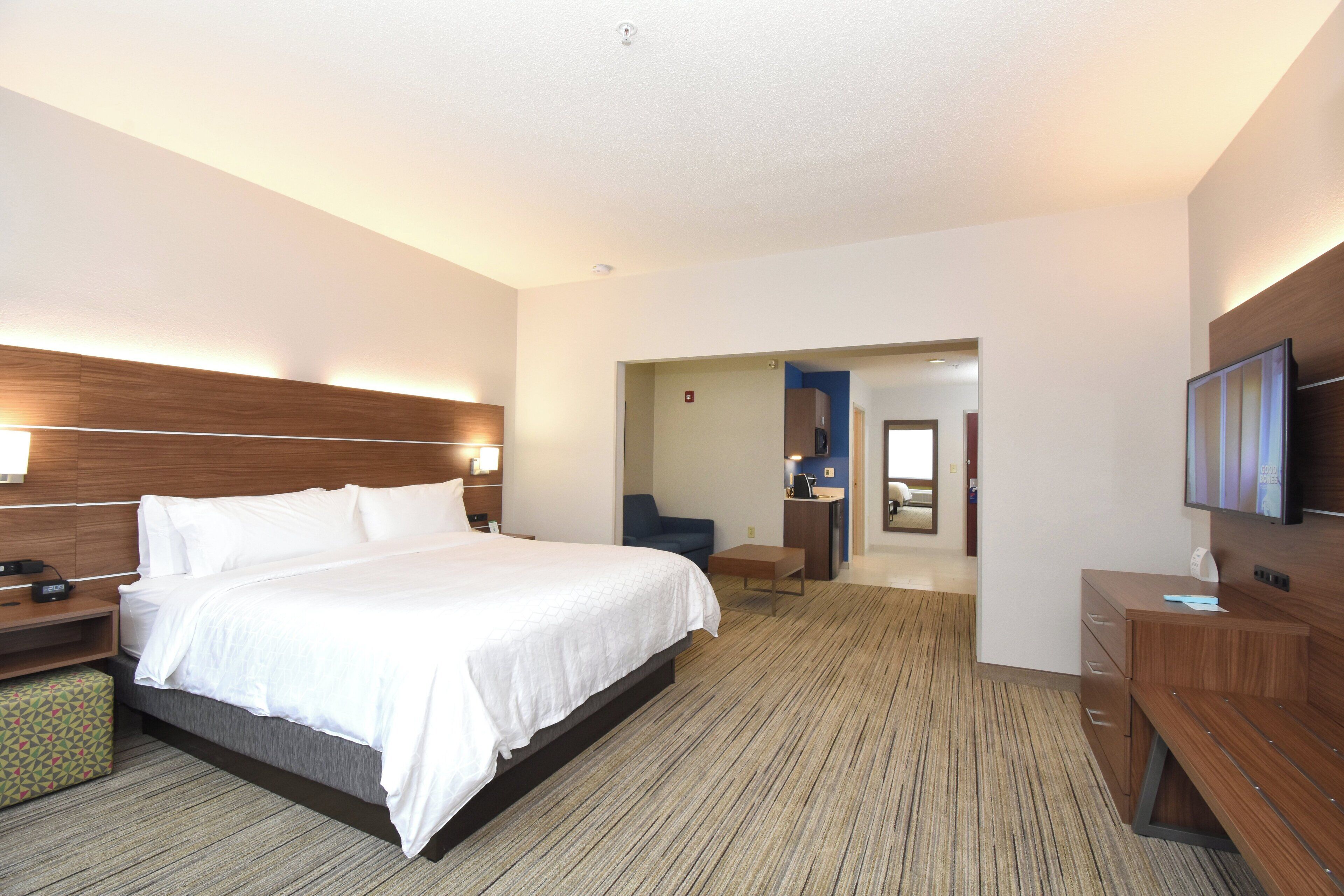 Hotelkamer met een groot bed, nachtkastjes, een bureau, een stoel, een televisie en een badkamer door een geopende deur zichtbaar.