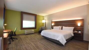 Una habitación de hotel con cama, escritorio, silla, lámpara y ventana.