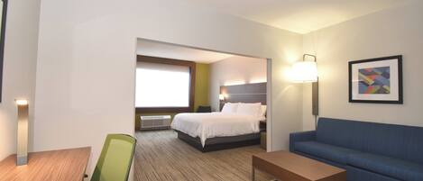 Una habitación de hotel con cama, sofá, escritorio y una silla.
