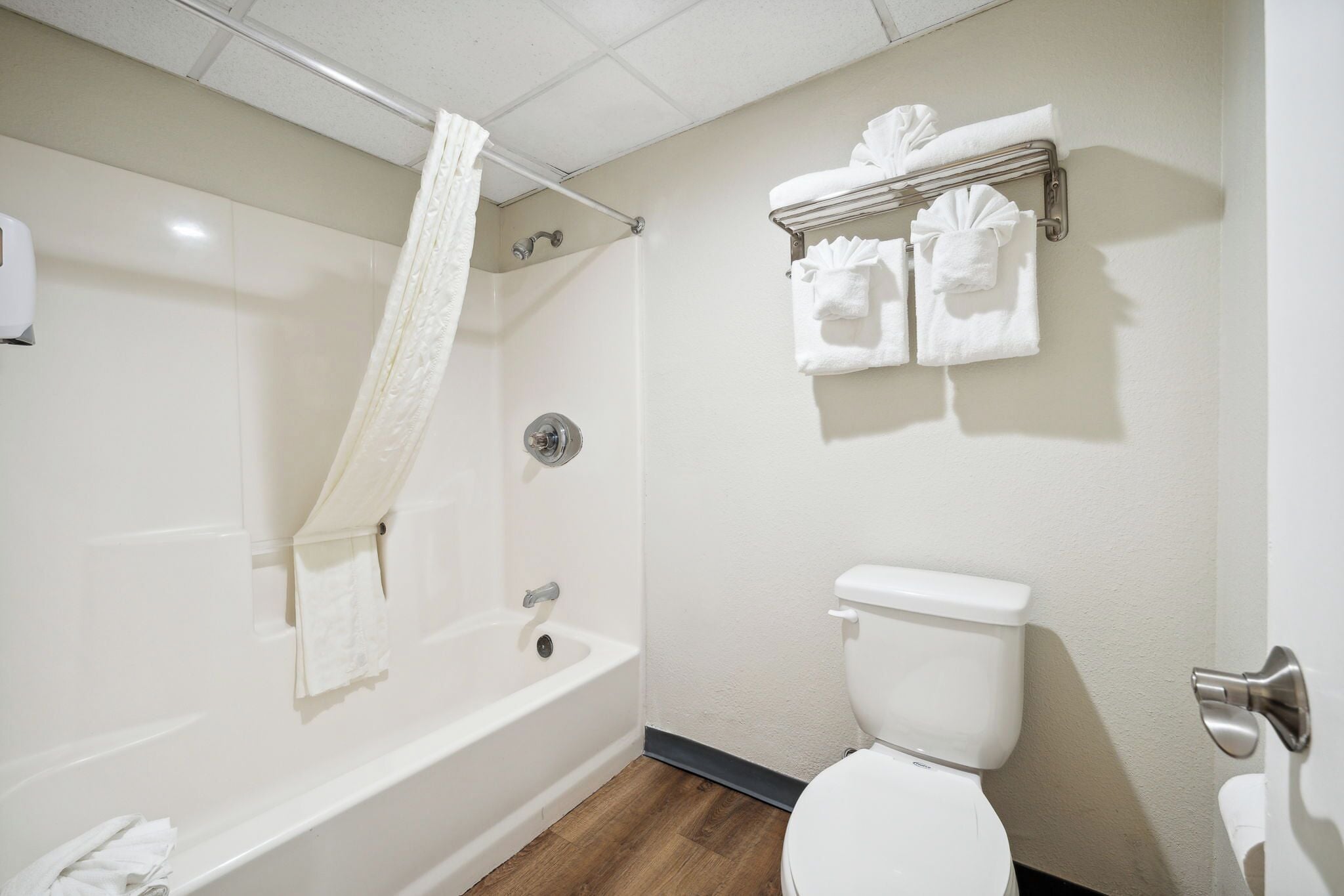 A bathroom with a bathtub, toilet, and a towel rack with towels.
