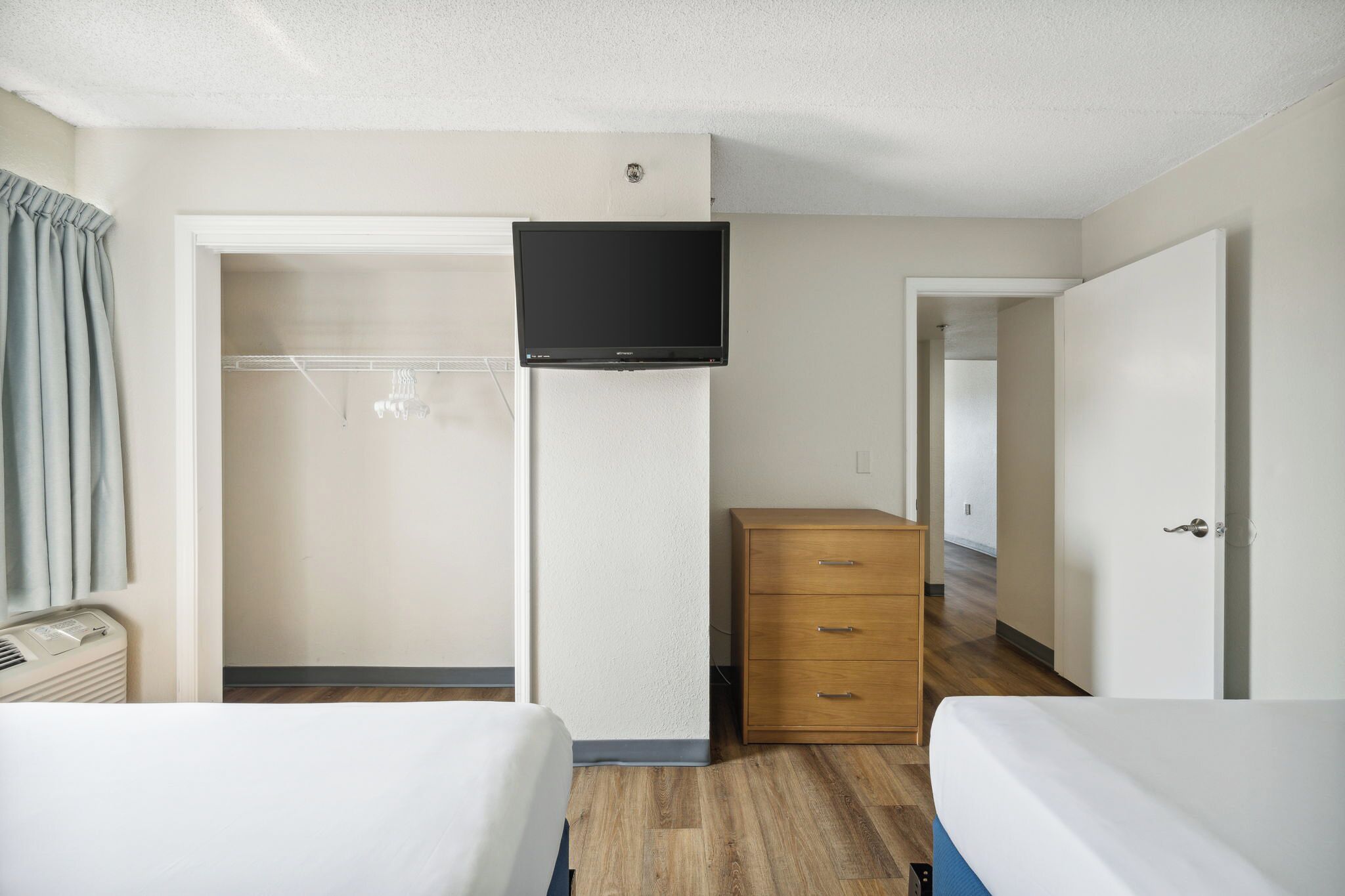 Une chambre d’hôtel comprenant un lit, une commode, un téléviseur fixé au mur et un placard.