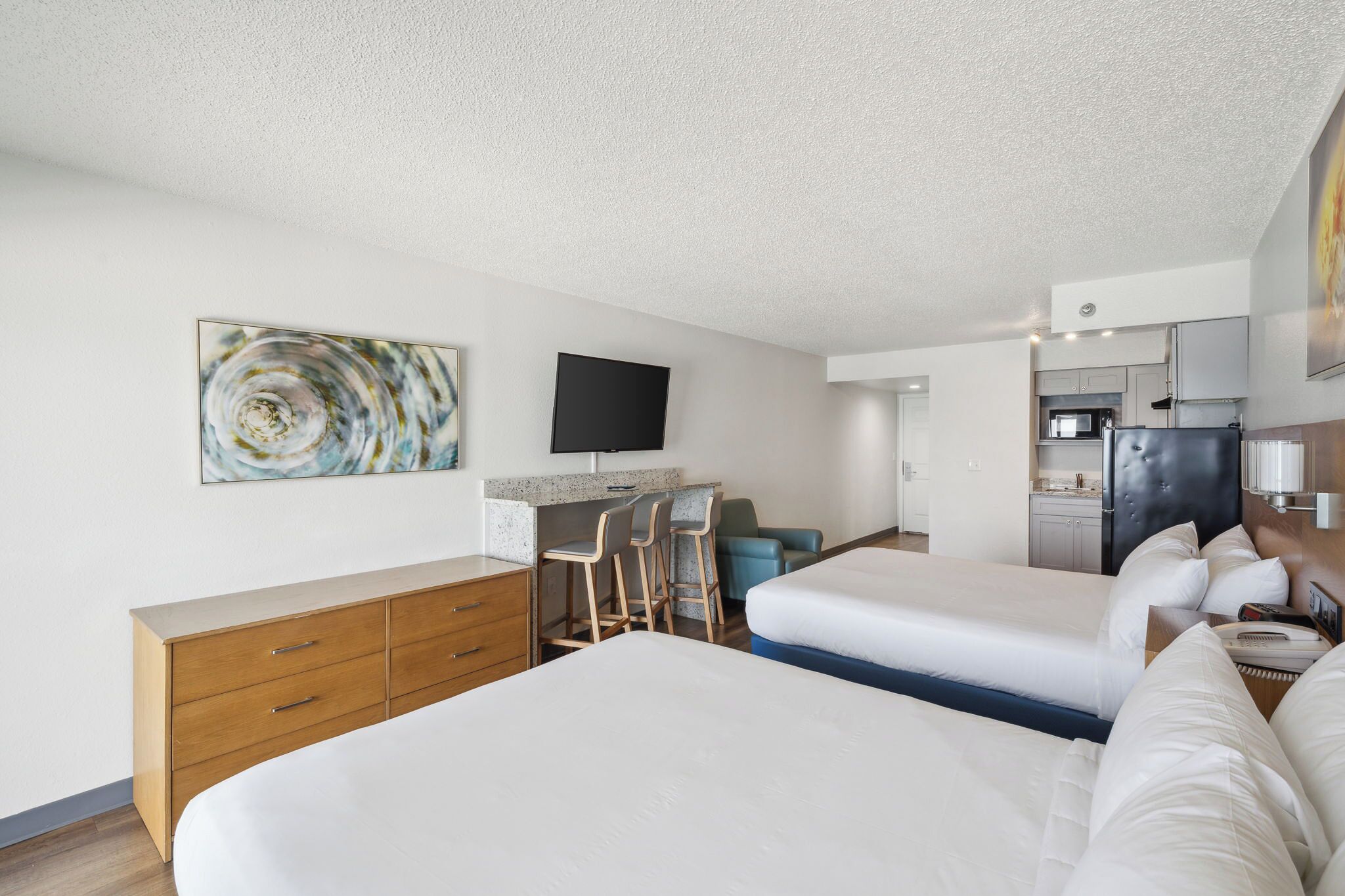Une chambre d’hôtel avec deux lits, un bureau, une télévision et une kitchenette.