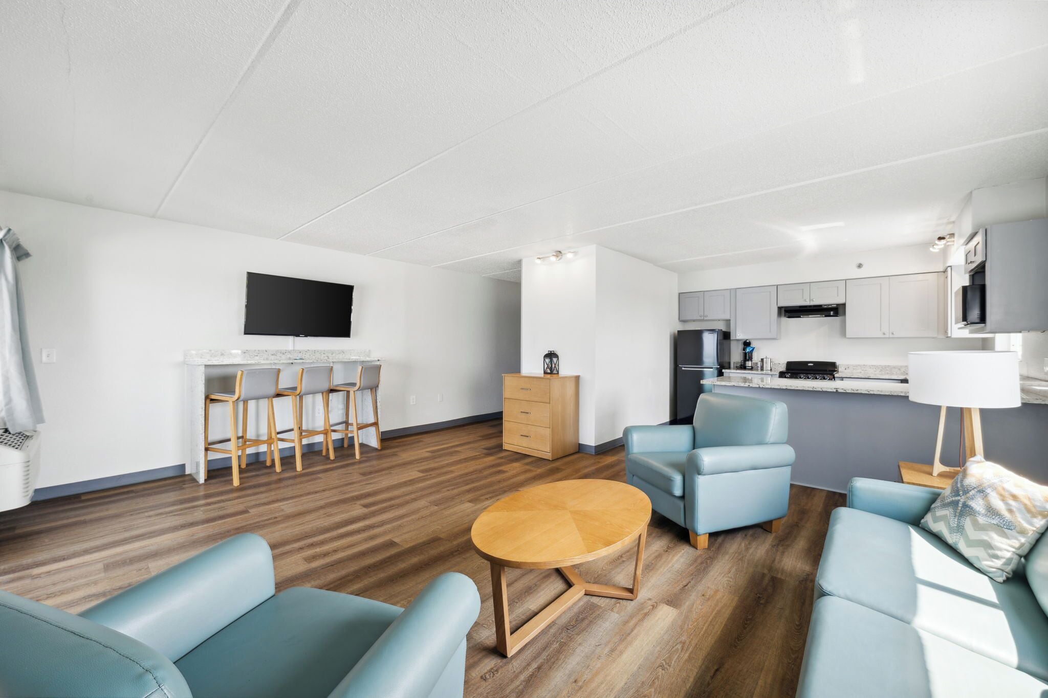 A modern living room with a wooden floor, a round coffee table, and light blue sofas.