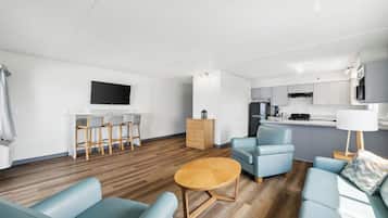 A modern living room with a wooden floor, a round coffee table, and light blue sofas.