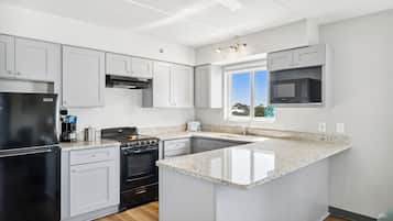 Una cocina moderna con armarios blancos, un refrigerador negro, una estufa y un microondas.