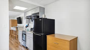 A kitchen with a black refrigerator, wooden cabinets, a microwave, and a stove.