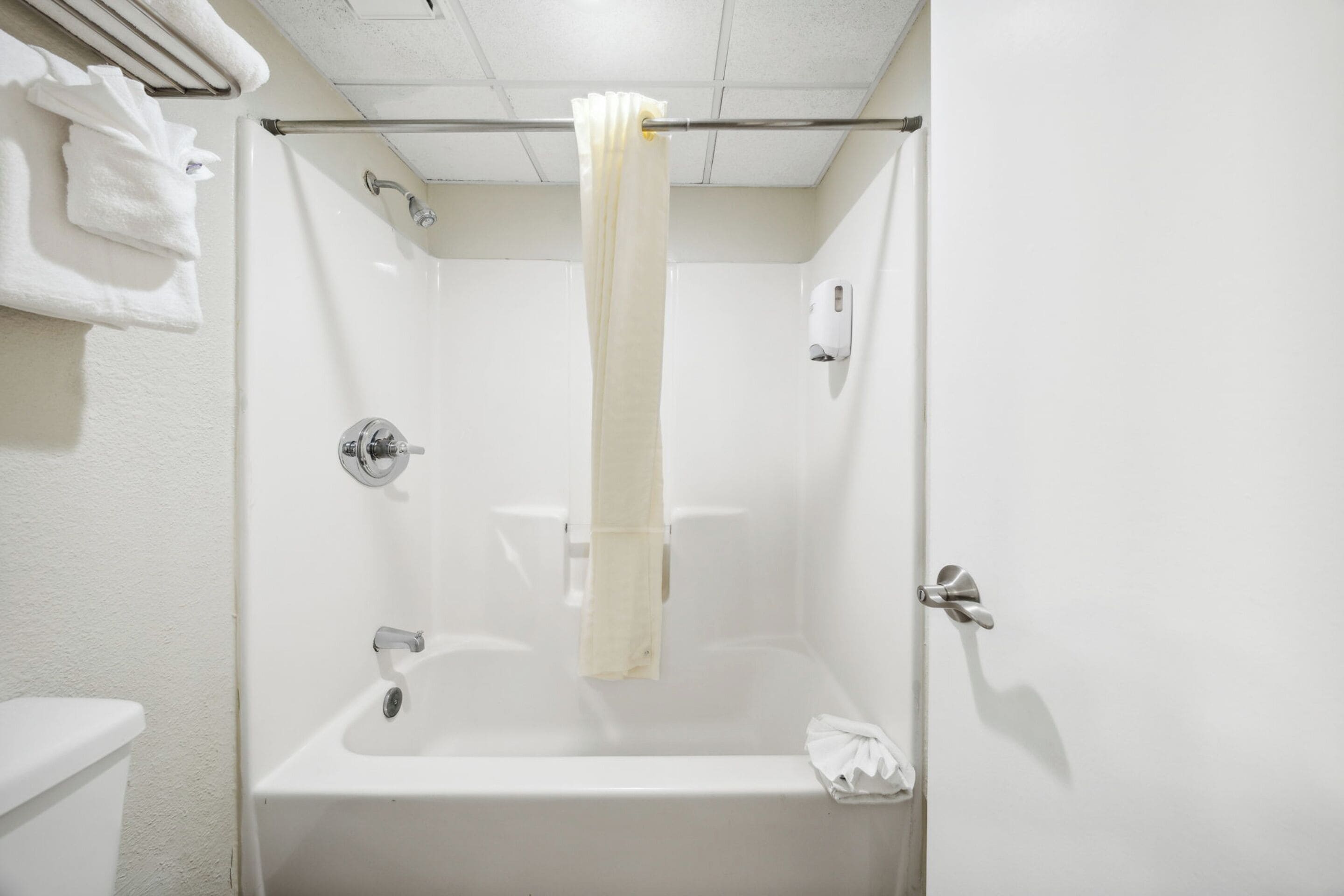 A white bathroom with a bathtub, a toilet, and a towel rack.