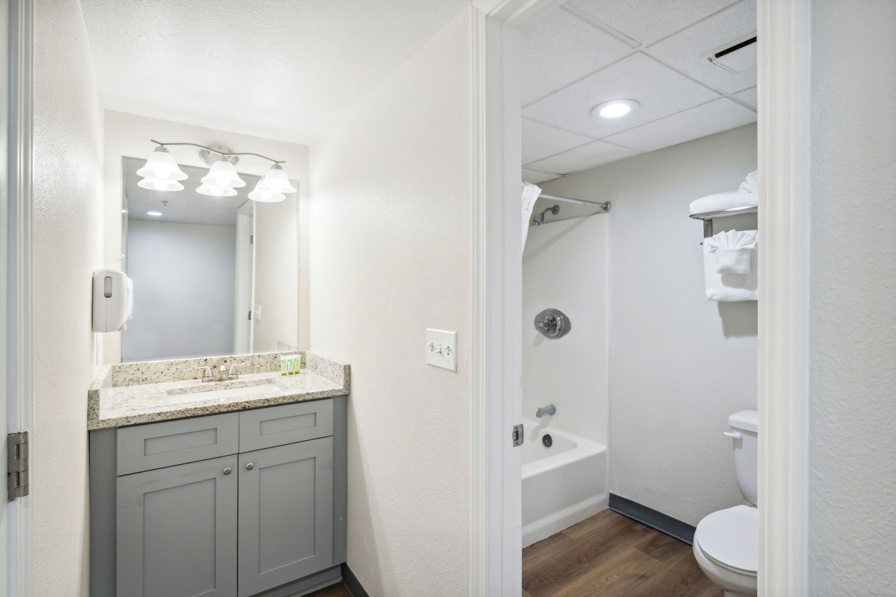 A bathroom with a sink, mirror, and a shower area.