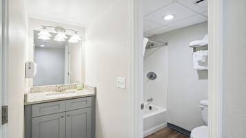 A bathroom with a sink, mirror, and a shower area.
