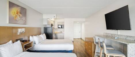 Habitación de hotel con dos camas, kitchenette, televisión y zona de comedor.
