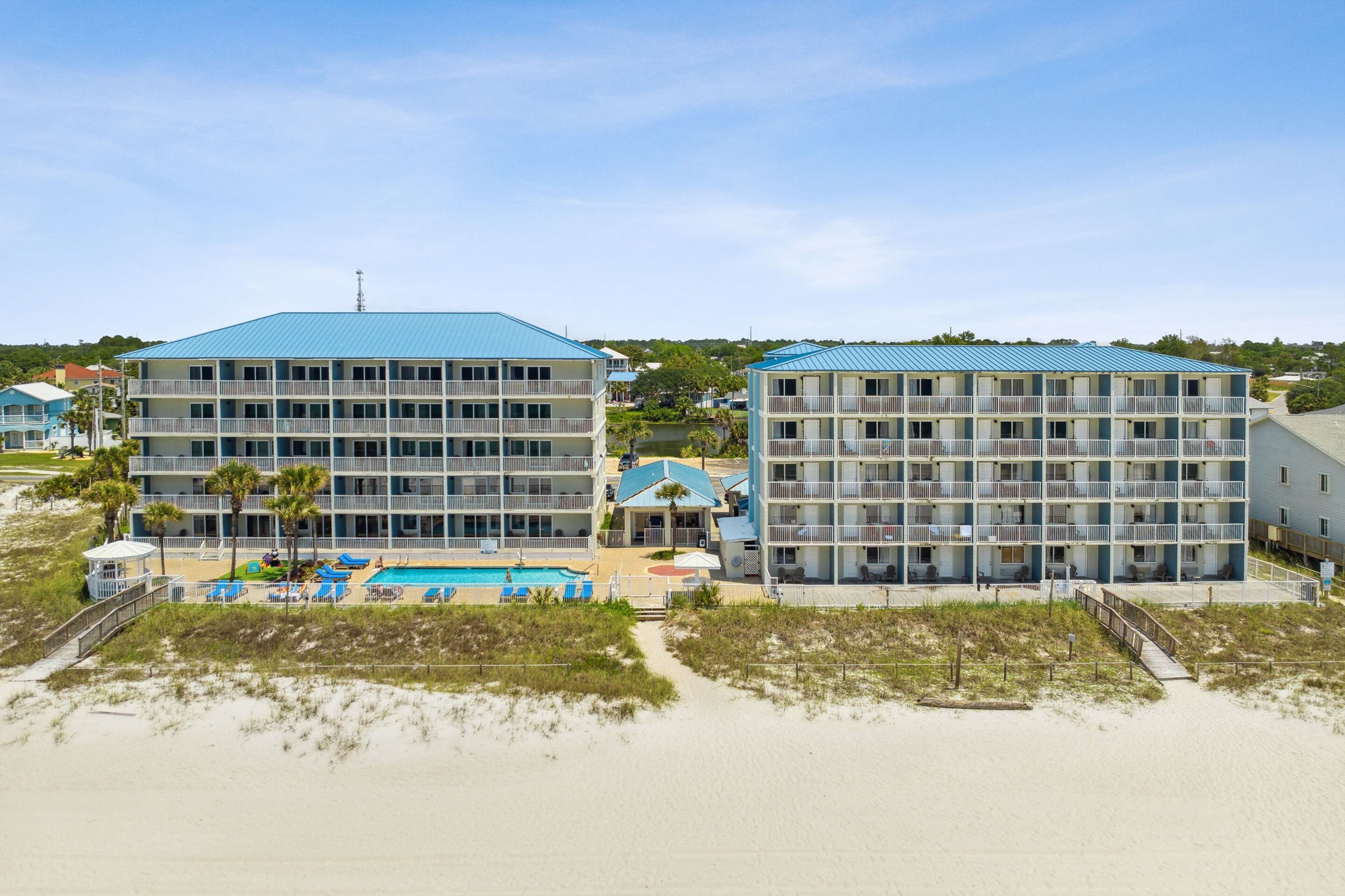A beachfront hotel with multiple balconies, a swimming pool, and a beach access walkway.