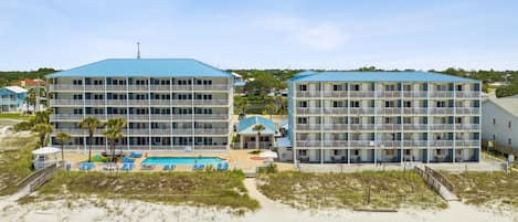 A beachfront hotel with multiple balconies, a swimming pool, and a beach access walkway.