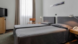 A hotel room with two beds, a desk with a telephone, a chair, a television, and a lamp. - Albergo Alla Posta (Trieste)