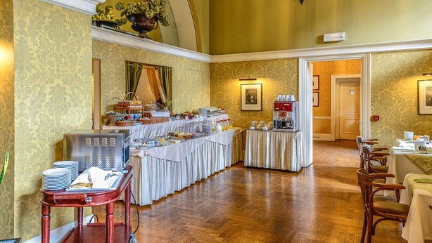 A dining area with buffet tables, a coffee station, and a large potted plant. - Albergo Alla Posta (Trieste)