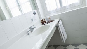 A modern bathroom with a white sink, a mirror, and a checkered floor. - Albergo Alla Posta (Trieste)