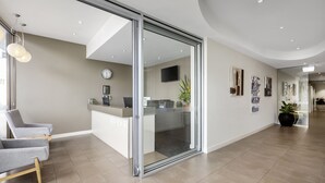 A modern reception area with a glass door, a reception desk, and a seating area with chairs. - Quest Ivanhoe (Ivanhoe)