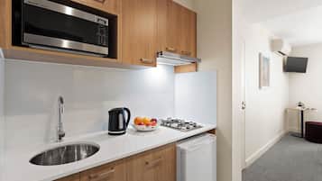 A modern kitchen with a stainless steel microwave, a gas stove, a sink, and wooden cabinets.