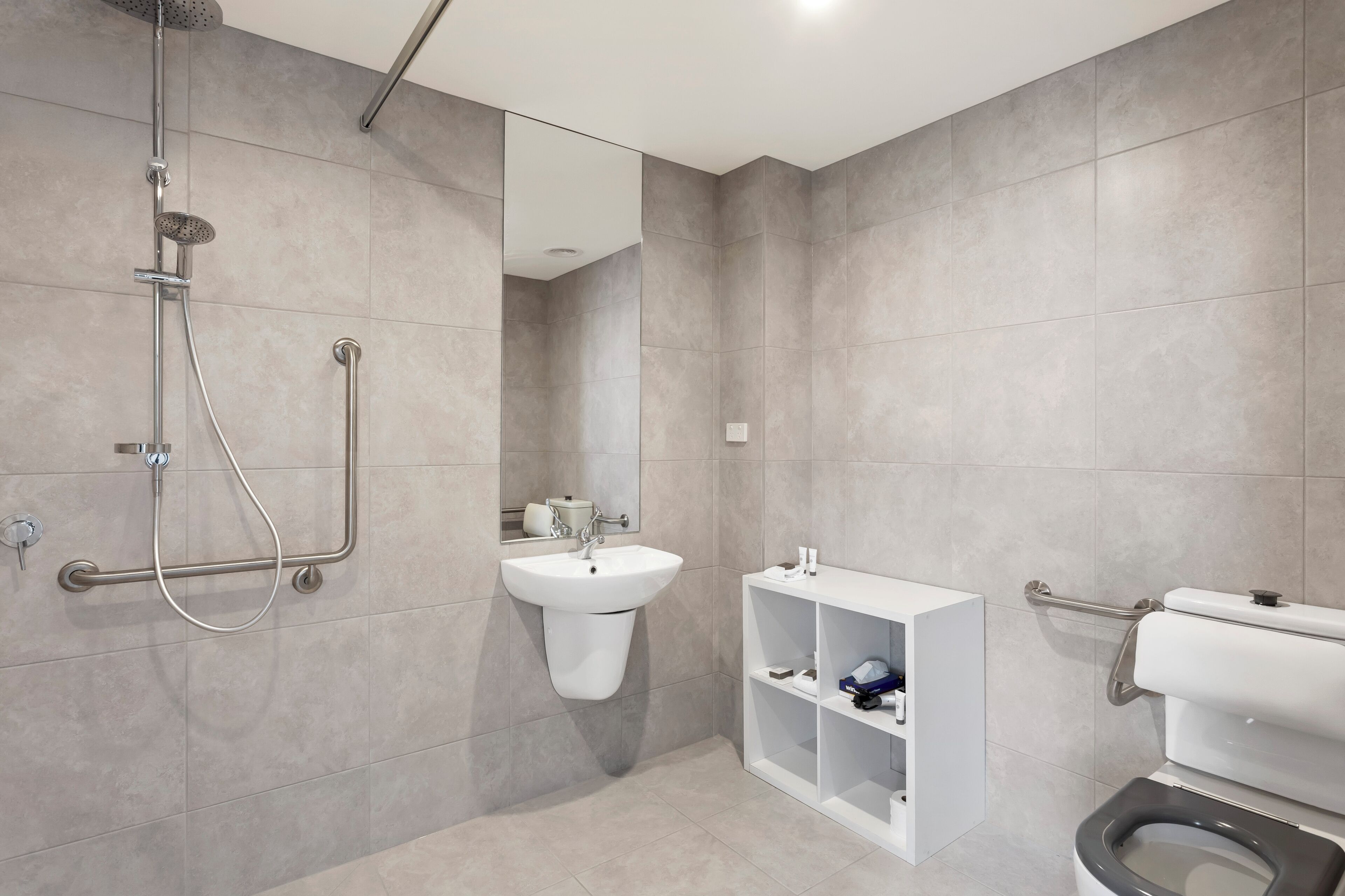 A modern bathroom with a walk-in shower, a pedestal sink, and a toilet.