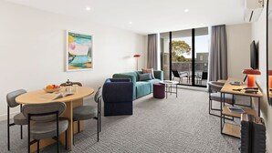 A modern hotel room with a sofa, a dining table, and a TV. - Quest Ivanhoe (Ivanhoe)