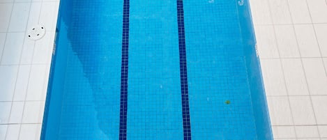 Une piscine rectangulaire aux carreaux bleus, avec deux séparateurs de couloirs de couleur bleu foncé.