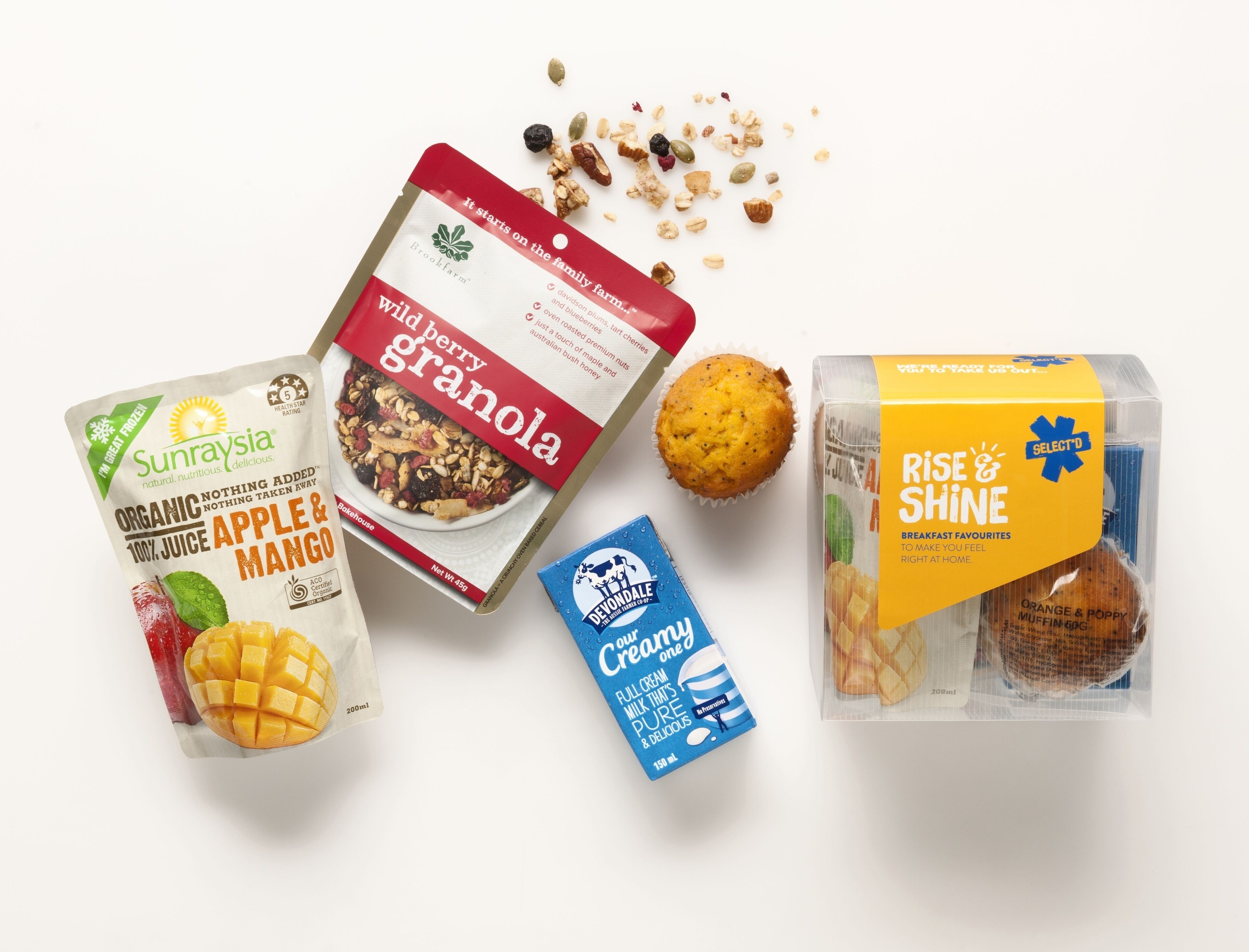 A variety of food items including granola, a muffin, a carton of milk, and a mango.