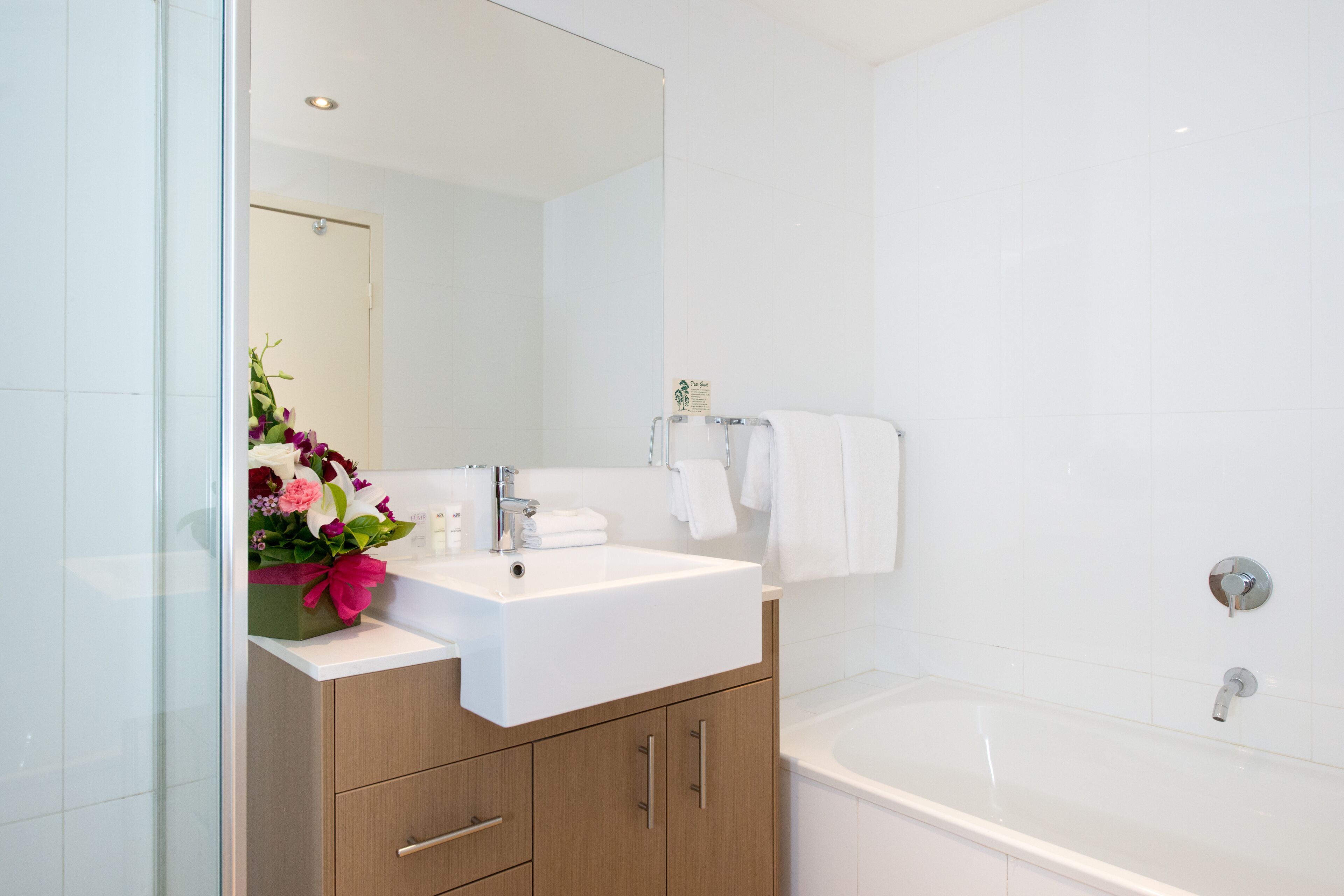 A modern bathroom with a white sink, a large mirror, and a bathtub.