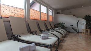 A spa room with reclining chairs, a massage table, and a large plant. - Hotel Krone (Matrei am Brenner)