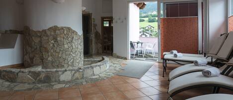 A spa area with a stone fireplace, a massage table, and a view of the outdoors.