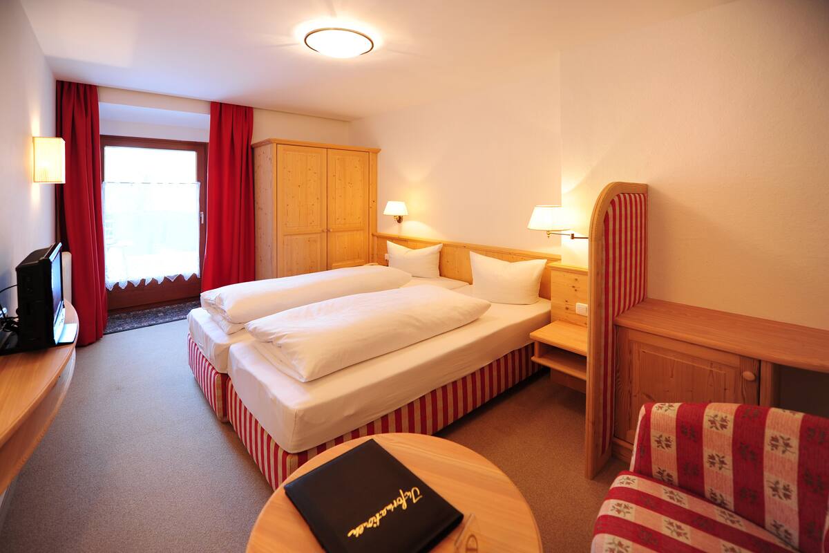 A hotel room with two beds, a desk, a chair, and a wardrobe.
