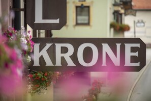 Un panneau de signalisation indiquant la rue « KRONE » et un panier de fleurs contenant des fleurs roses et rouges.