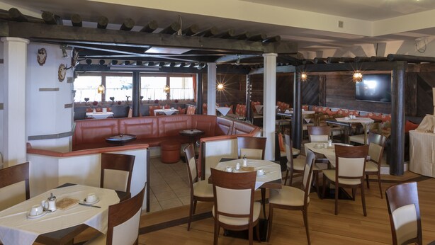 A restaurant with booths, tables, and chairs. - Hotel Krone (Matrei am Brenner)