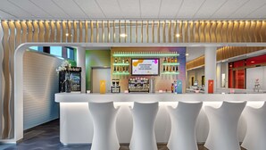 Eine moderne Bar mit einer gebogenen Theke, weißen Barhocker und einer Auswahl an Getränken in Regalen.