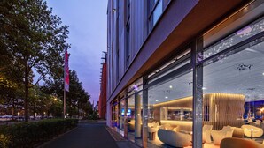 Ein modernes Hotel mit großen Glasfenstern, zeitgemäßer Inneneinrichtung und einem gut beleuchteten Zugang.