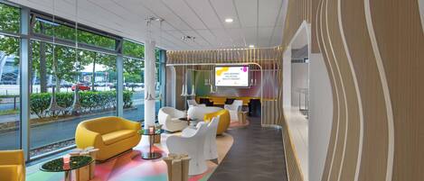 A modern lobby with a curved seating area, large windows, and a digital display.