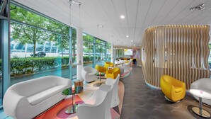 Ein modernes Interieur mit Sitzbereichen, einer gebogenen Holzwand und großen Fenstern mit Blick ins Freie.